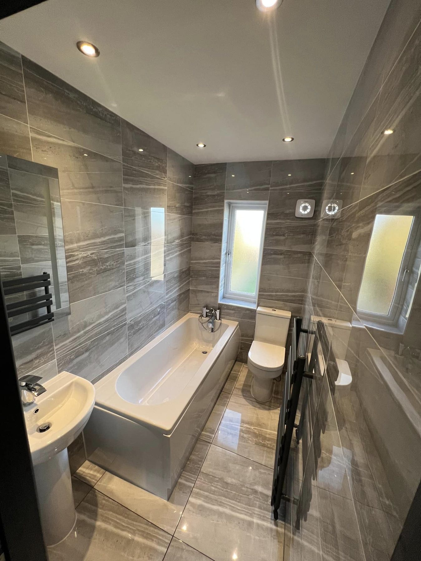 Finished rental bathroom with grey wall tiles